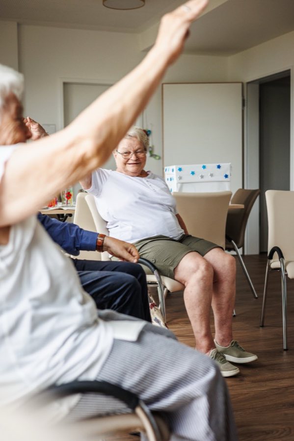 Seniorinnen bei der Sitzgymnastik im Aufenthaltsraum der Tagespflege