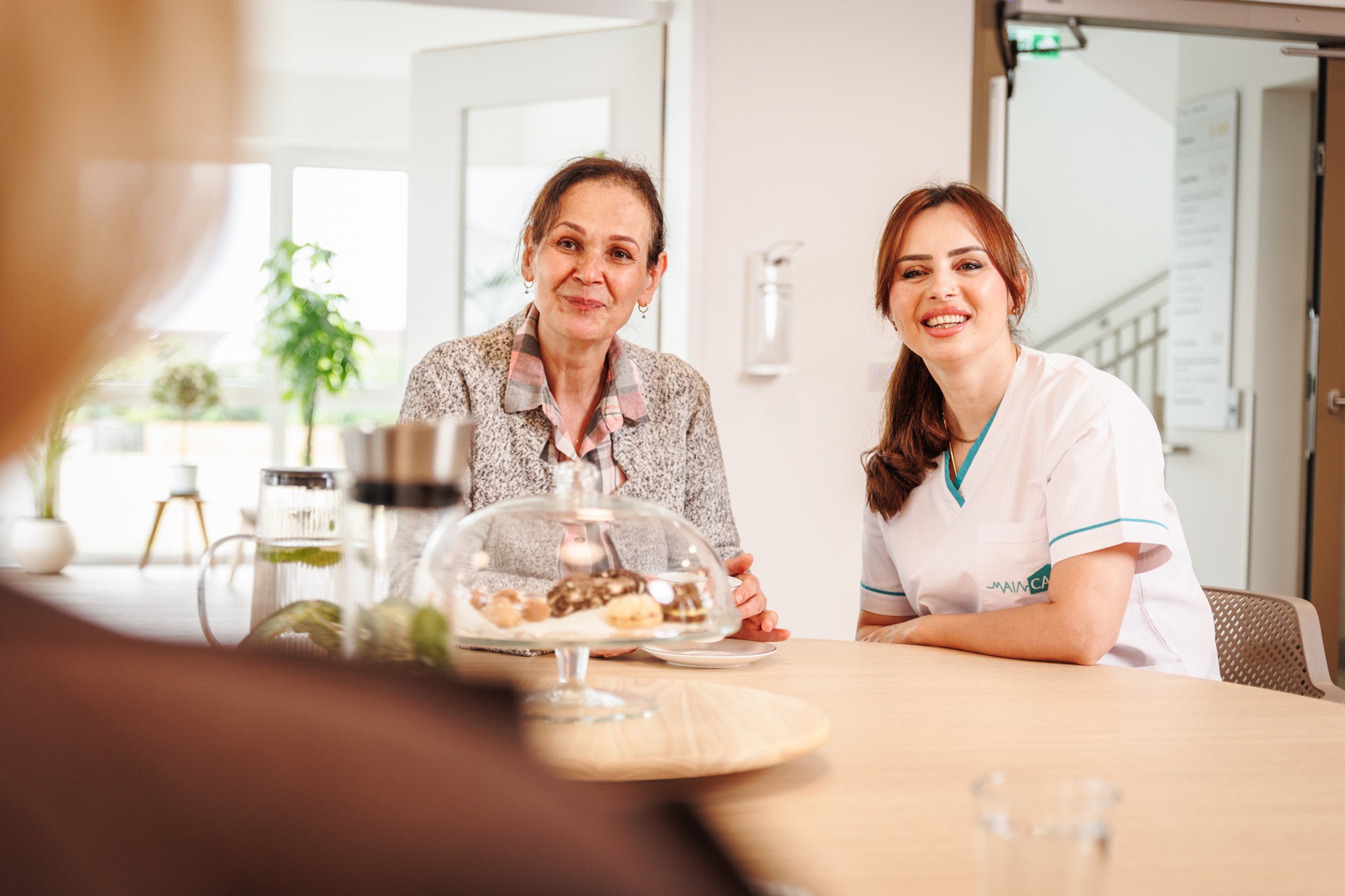 Seniorin und Pflegefachkraft beim gemeinsamen Essen in der Tagespflege Erlensee