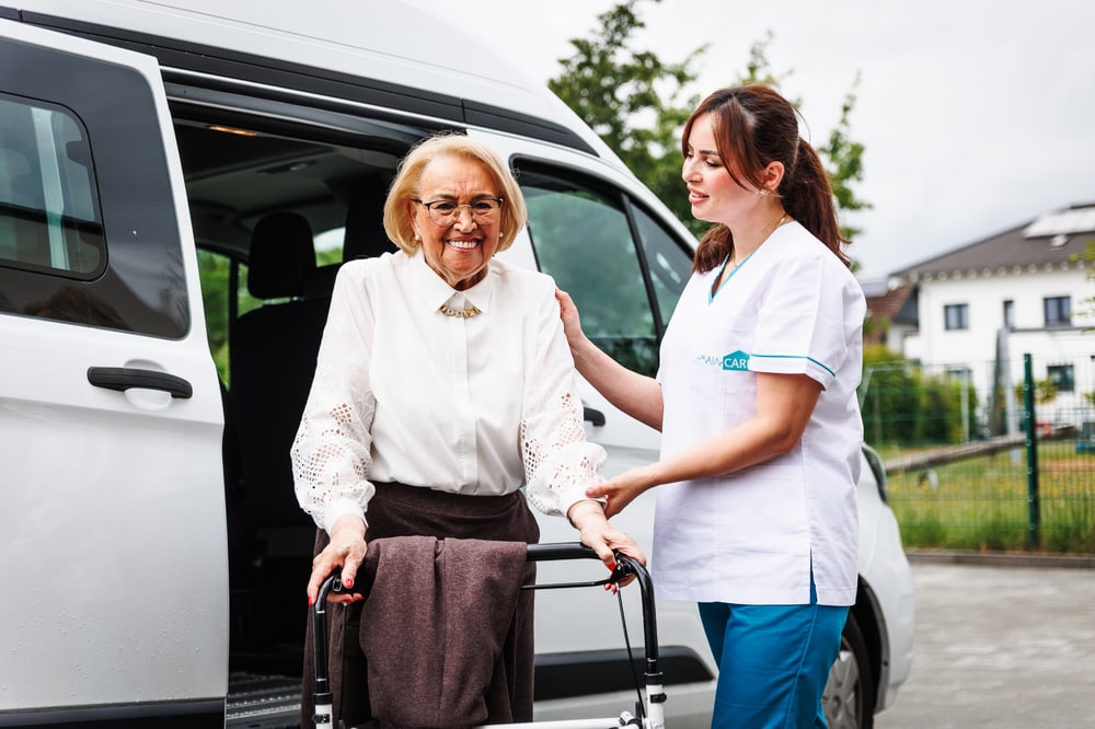 Pflegefachkraft begleitet einen Patienten mit Rollator im Alltag