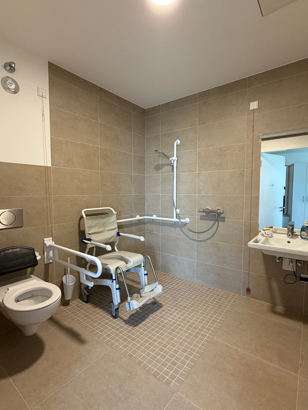 Barrierefreies Bad mit offener Dusche und Duschstuhl im Intensivpflege-Apartment